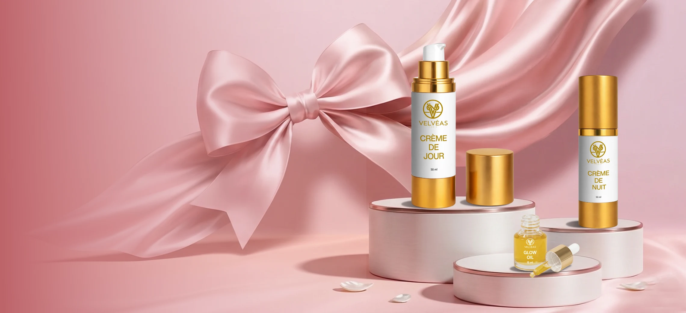 Trio de soins Velvéas sur podium rose – Crème de Jour 50 ml, Crème de Nuit 50 ml et Glow Oil 15 ml avec nœud satiné rose et voile de soie